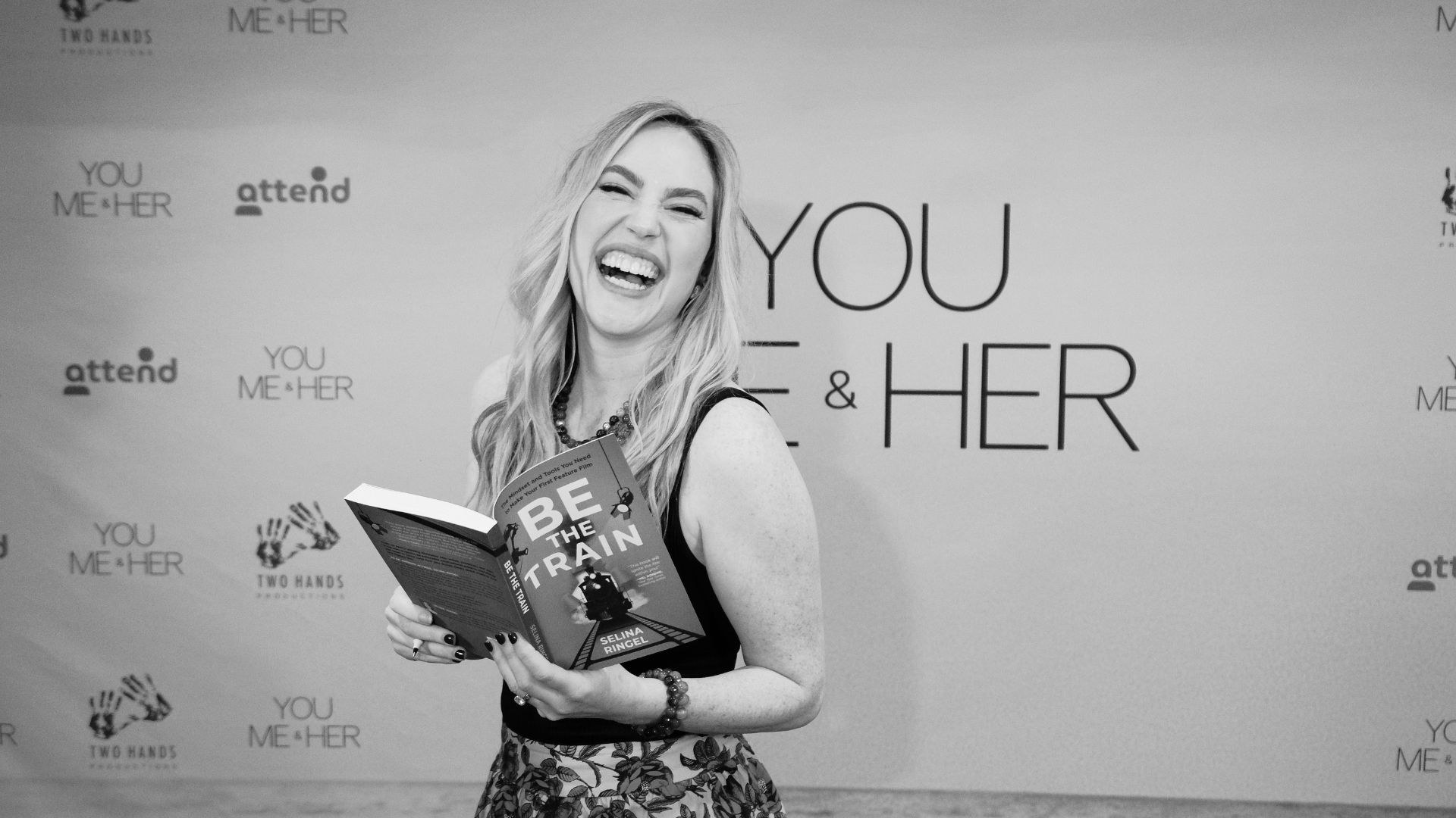 Selina Ringel laughing as she holds a copy of Be The Train at a You, Me & Her screening