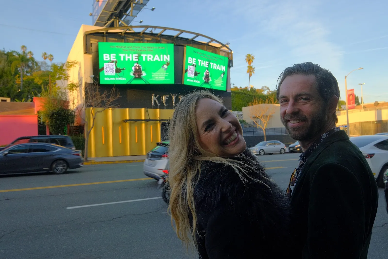 Selina & Dan on Sunset Blvd in front of the Be The Train billboard